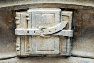 Detail of architectural stone carving depicting three books bound with a belt.